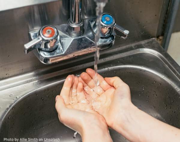 A person washing their hands at a sink.